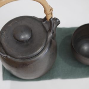 Théière céramique_grès brun foncé noir_anse bois_ L'Inatelier_Nantes_fabrication artisanale française_ bretagne_en situation avec bol et serviette _vue du dessus